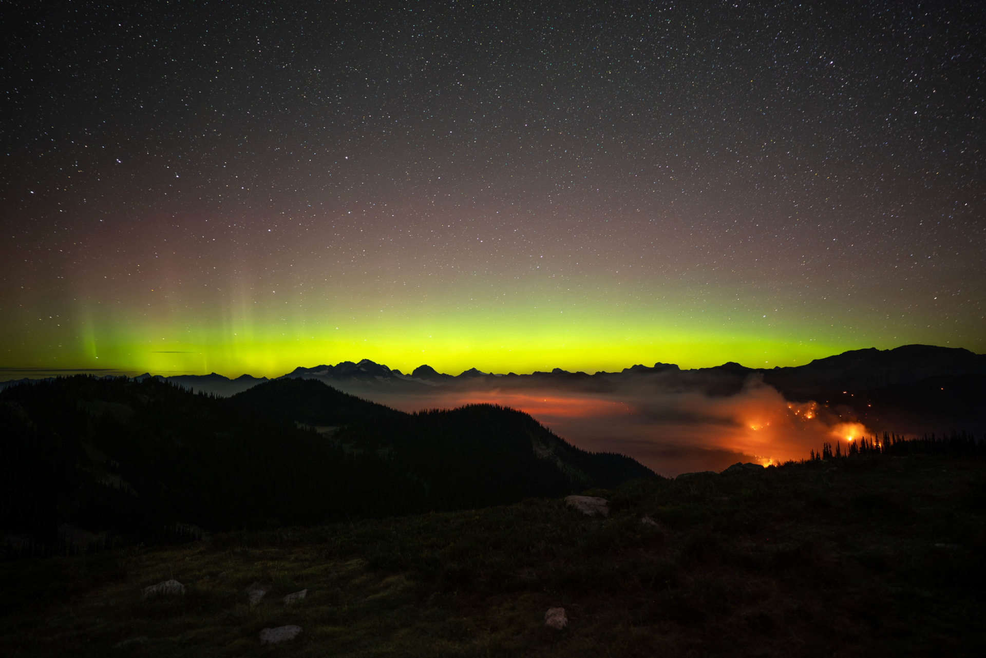 Northern lights over a wildfire in the valley bottom